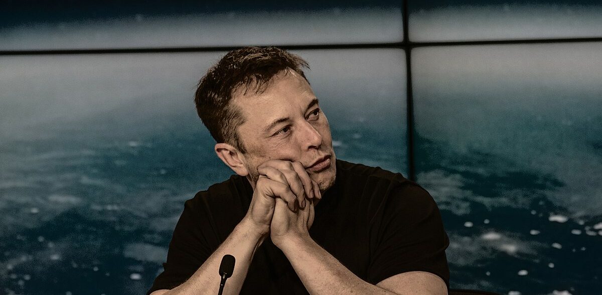 Elon Musk; Elon Musk zittend aan een tafel tijdens persconferentie
