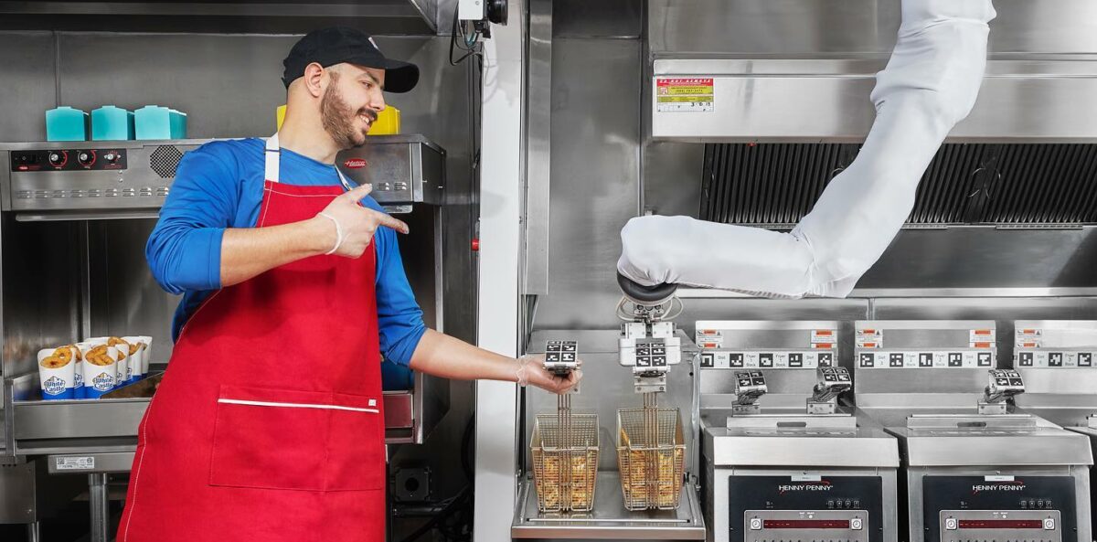 Robot Restaurant; een man die naast de robotarm staat die friet maakt.