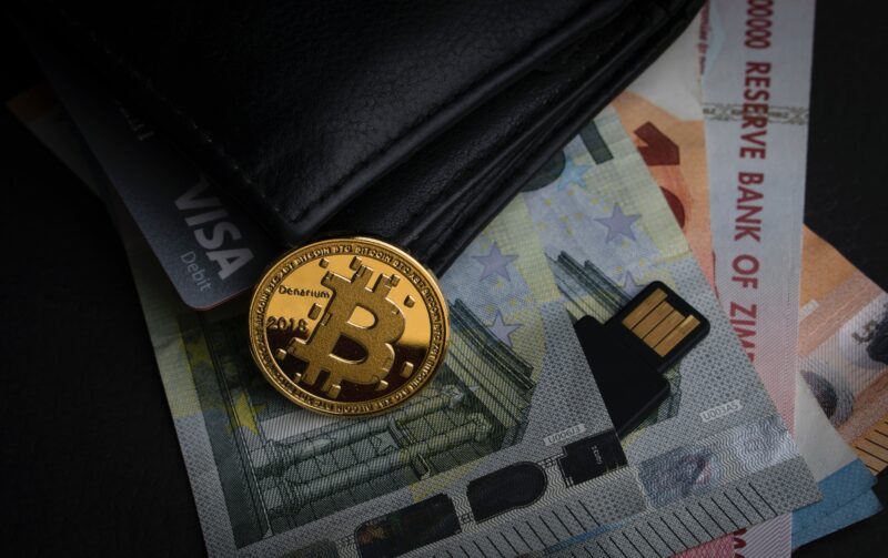 Crypto Fouten; bitcoin naast een fysieke wallet met fysieke valuta