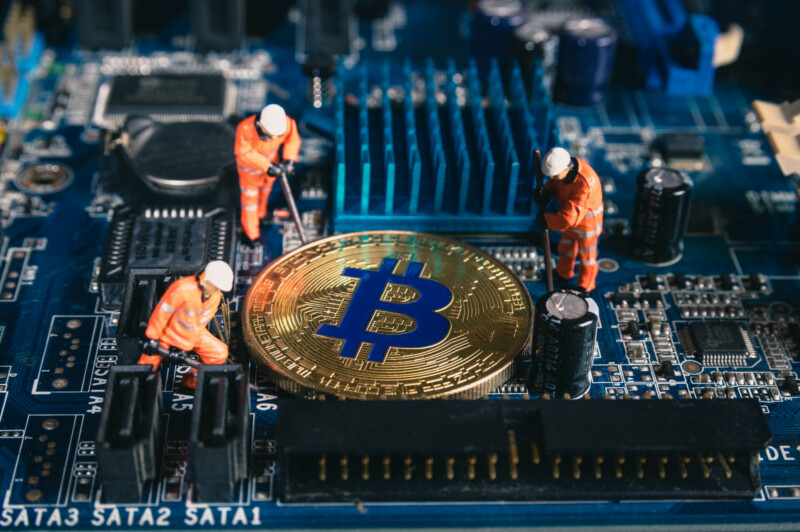 Crypto Minen; twee mijnwerkers op een moederbord van een hardware computer die een Bitcoin delven